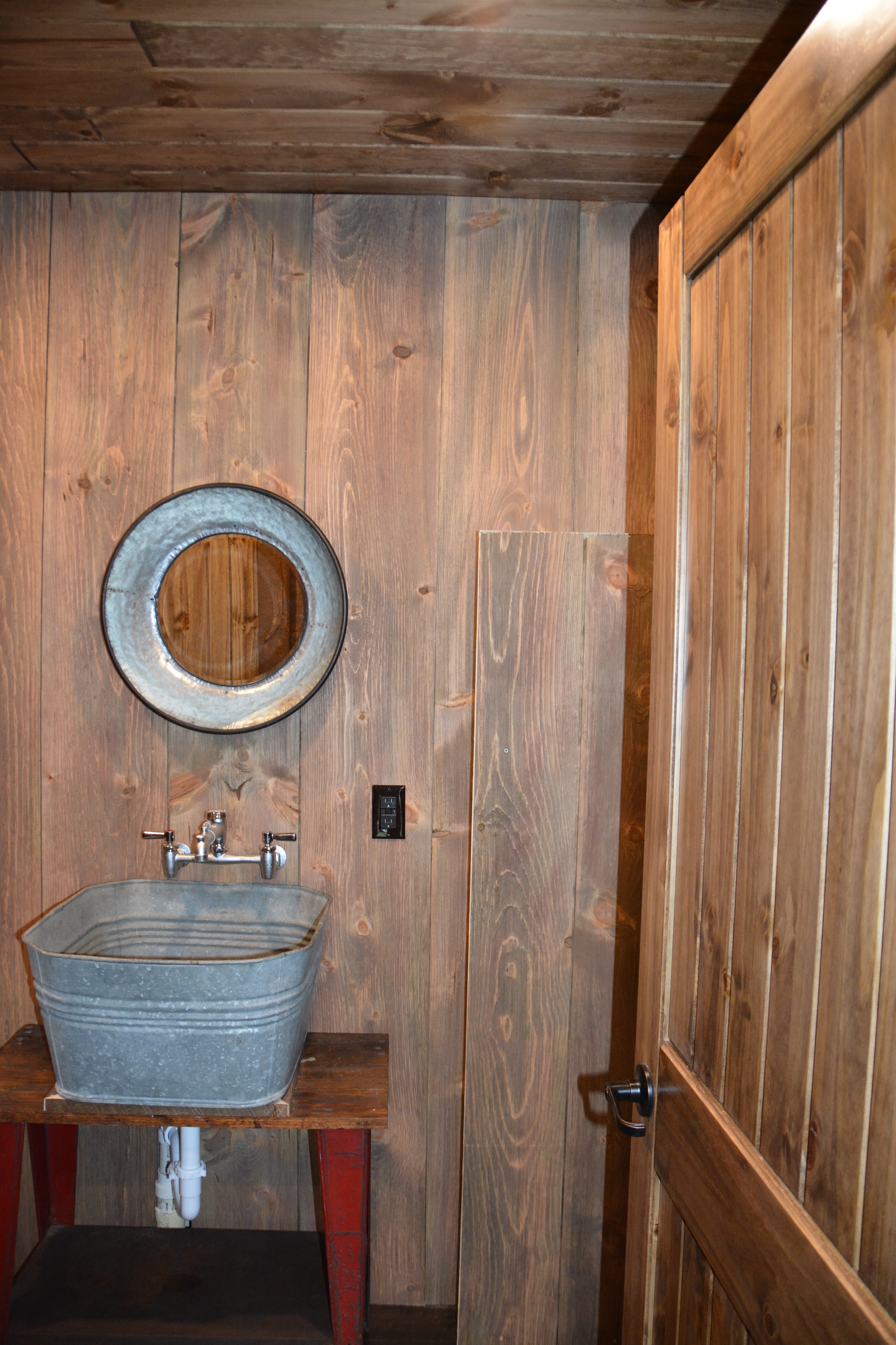 Powder room with circle sawn barn wood in weathered red with steel mirror and sink vanity.